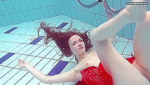 Sexy redhead takes off her bathing suit in the pool